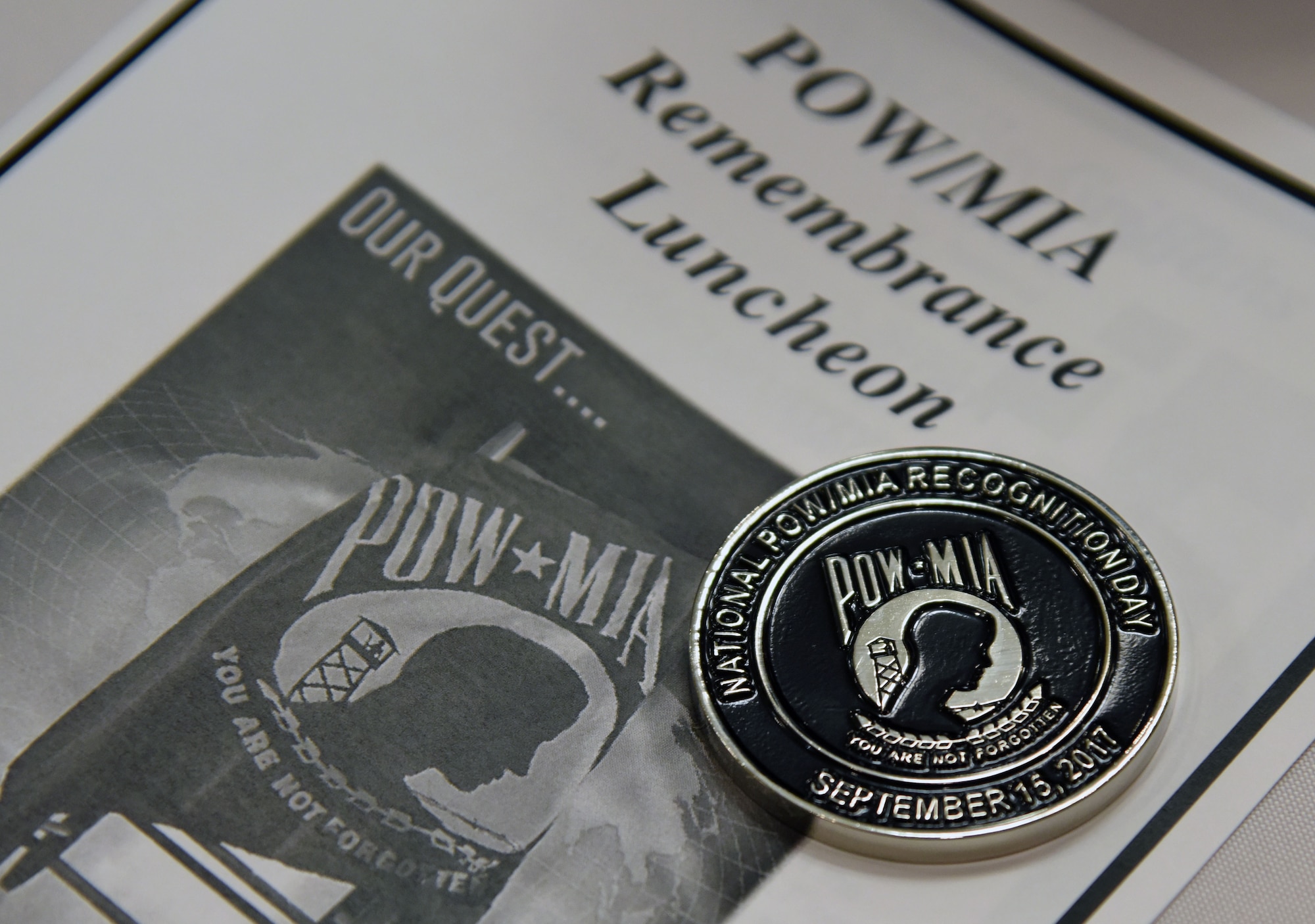 A commemorative coin and event pamphlet is on display during a POW/MIA Remembrance Luncheon at the Bay Breeze Event Center Sept. 13, 2017, on Keesler Air Force Base, Mississippi. The event, hosted by the Air Force Sergeants Association, was held to raise awareness and pay tribute to all prisoners of war and military members still missing in action. (U.S. Air Force photo by Kemberly Groue)