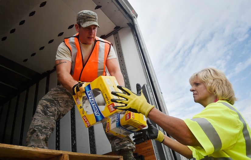 Staff Sgt. Micah Hallman, left, 43rd Air Mobility Squadron air transportation specialist, Pope Army Airfield, N.C., hands boxes to Jodi Johnson, right, U.S. Department of Homeland Security - Federal Emergency Management Agency (FEMA), as they download goods and commodities in support of Hurricane Irma relief efforts at Joint Base Charleston’s North Auxiliary Airfield, S.C., Sept. 13, 2017. The airfield acts as a receiving and distribution staging area for goods and commodities to be transported to hurricane victims here and areas of the southeast over the next few weeks. Airmen of the 43rd Air Mobility Operations Group and FEMA are working side-by-side executing relief efforts. (U.S. Air Force photo by Staff Sgt. Christopher Hubenthal)