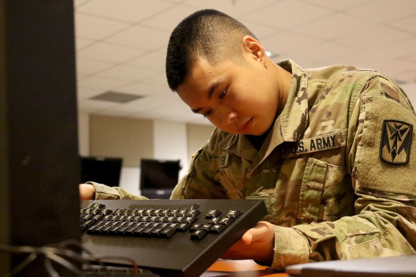 Army Pfc. Dorold Nguyen, a Patriot Fire Control Enhanced Operator/Maintainer with Headquarters and Headquarters Battery, 35th Air Defense Artillery Brigade, inspects the Reconfigurable Table Top Trainer’s keyboard.