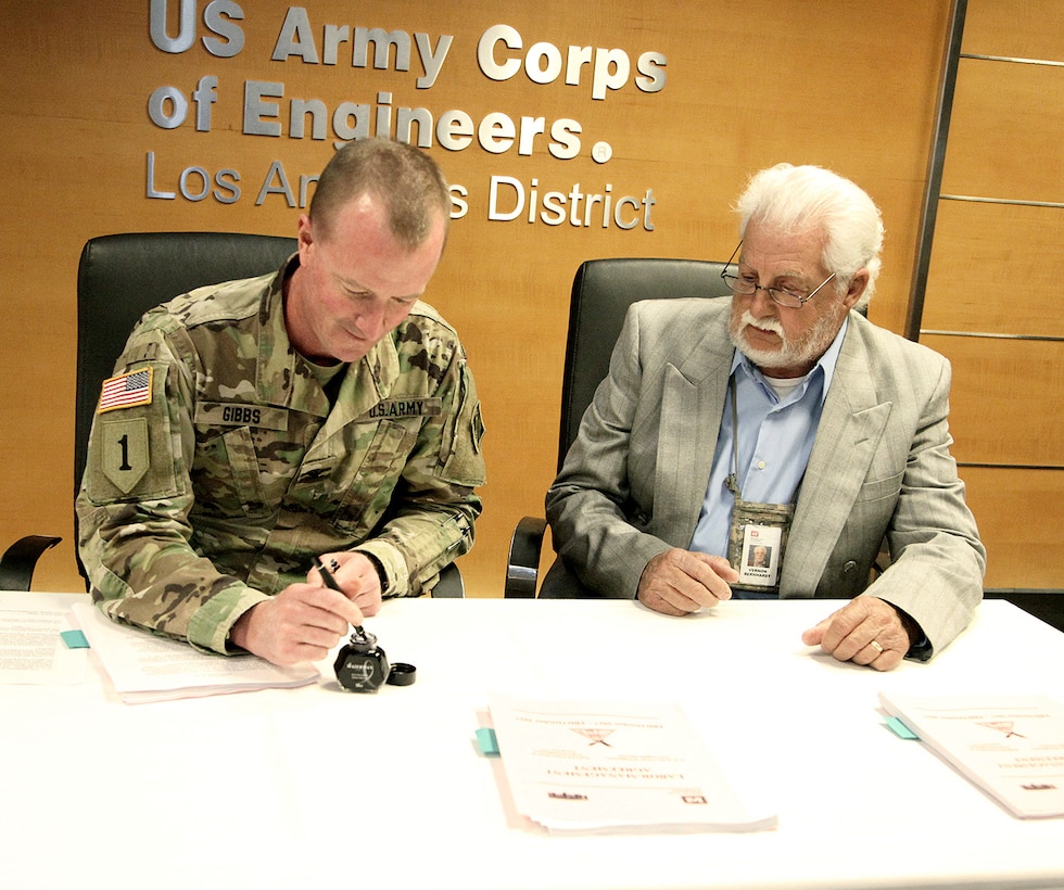 Col. Kirk Gibbs, commander of the U.S. Army Corps of Engineers Los Angeles District, left, signs the labor-management agreement between the District and its Union, as Vern Bernhardt, president of the National Federation of Federal Employees Union Local Chapter No. 777, looks on during a Sept. 12 signing ceremony at the District’s office in downtown LA.