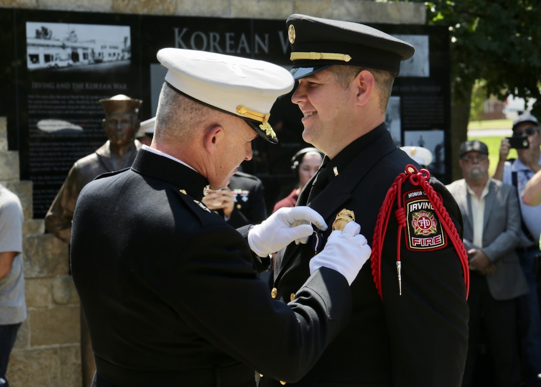 Retired Marine Staff Sgt. Eric Smith is awarded the Navy Cross by Maj. Gen. Paul J. Kennedy during a ceremony in Irving, Texas, Sept. 14. Smith was awarded the Navy Cross for courageous actions in 2004 while serving as a squad leader with Company E, Second Battalion, Fourth Marine Regiment, First Marine Division, in support of Operation Iraqi Freedom. Smith currently serves as a lieutenant paramedic with the Irving Fire Department. Kennedy is the commanding general of Marine Corps Recruiting Command and commanded 2nd Battalion, Fourth Marines at the time of Smith's actions. The Navy Cross is the second highest military decoration that may be awarded to a member of the United States Navy, U.S. Marine Corps, (and to members of the Coast Guard when operating under the authority of the Department of the Navy). It is awarded for extraordinary heroism. (U.S. Marine Corps photo by Sgt. Courtney G. White)
