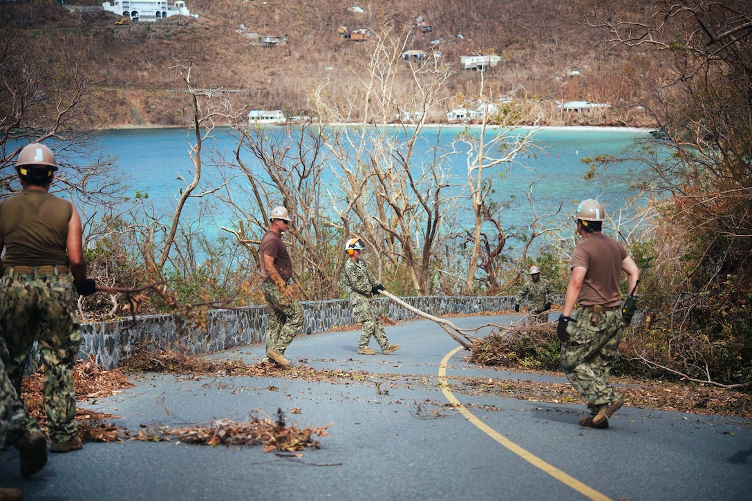 Seabees use shovels to clear away branches and debris.