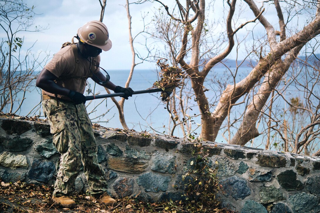 A Seabee uses a shovel to clear away debris.