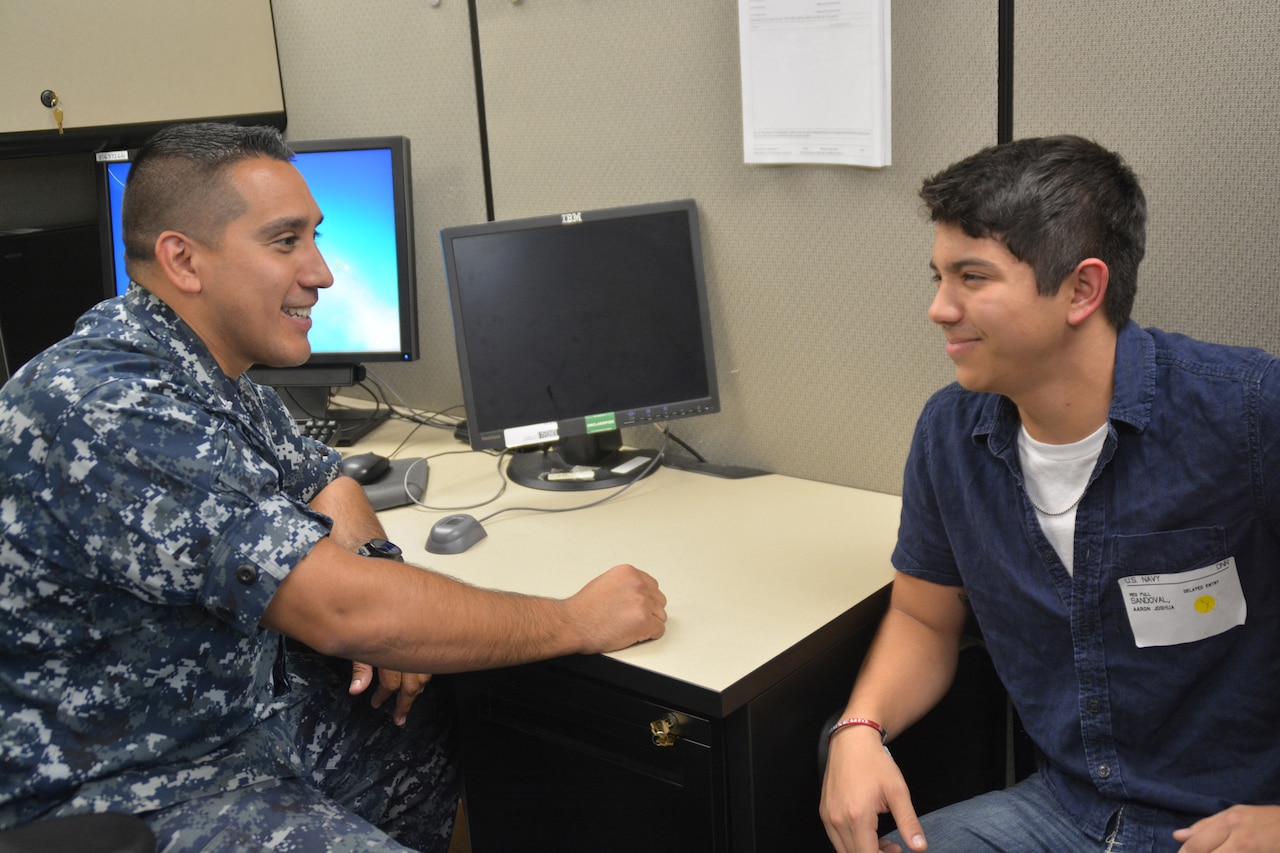 Navy Petty Officer 1st Class Christopher Thomas, a master-at-arms and recruiter assigned to Navy Recruiting District San Antonio, speaks with future sailor Aaron Sandoval