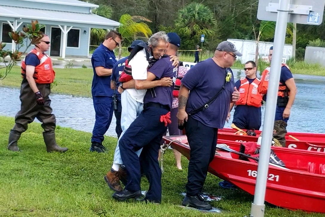 A member of the Coast Guard lifts a civilian.