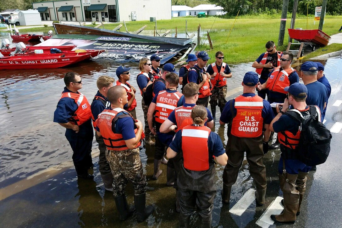 Members of the Coast Guard gather together on a street.