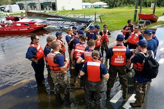 Members of the Coast Guard gather together on a street.