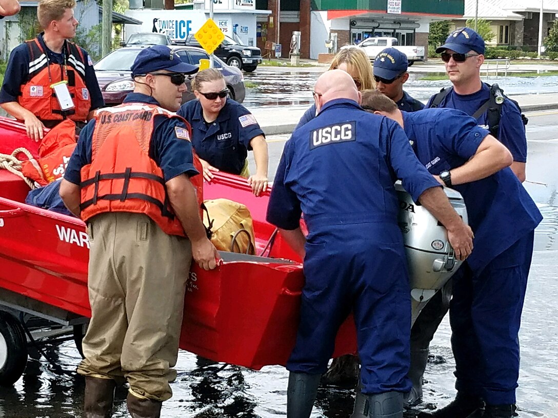 Members of the Coast Guard lower a boat into the flood waters.