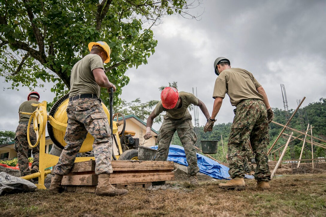 Service members in hard hats work at a construction site.