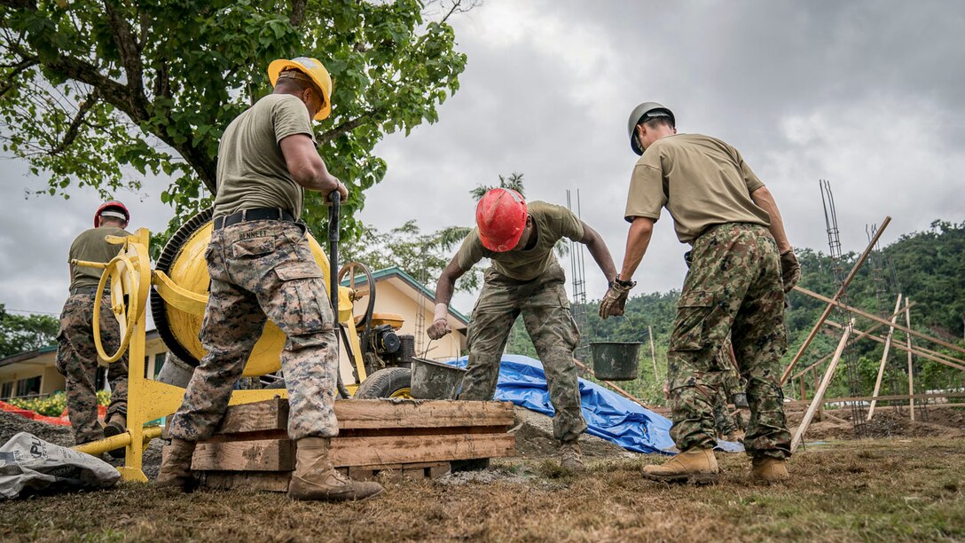 Service members in hard hats work at a construction site.