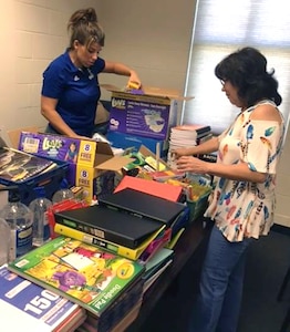 Dr. Jill Blankenship, principal of Blaschke Sheldon Elementary in the Ingleside Independent School District; Sylvia Elizondo, the superintendent's administrative assistant, unpack supplies donated by Robert G. Cole Middle and High School at Joint Base San Antonio-Fort Sam Houston.