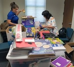 Dr. Jill Blankenship, principal of Blaschke Sheldon Elementary in the Ingleside Independent School District and Sylvia Elizondo, the superintendent's administrative assistant, open supplies donated by Robert G. Cole Middle and High School at Joint Base San Antonio-Fort Sam Houston.