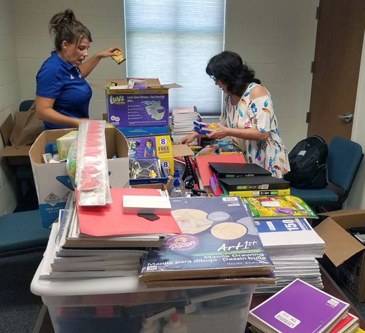 Dr. Jill Blankenship, principal of Blaschke Sheldon Elementary in the Ingleside Independent School District and Sylvia Elizondo, the superintendent's administrative assistant, open supplies donated by Robert G. Cole Middle and High School at Joint Base San Antonio-Fort Sam Houston.