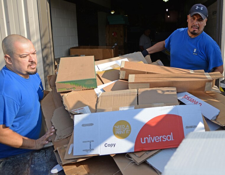 Mike Cardenas and Roland Deleon, Laughlin Air Force Base, Texas recyclers, tosses cardboard into a flatbed at the aircraft engine workshop here Sept. 15, 2017. Cardenas and Deleon, who both are prior service members, have more than 20 years’ combined experience in recycling at the facility.