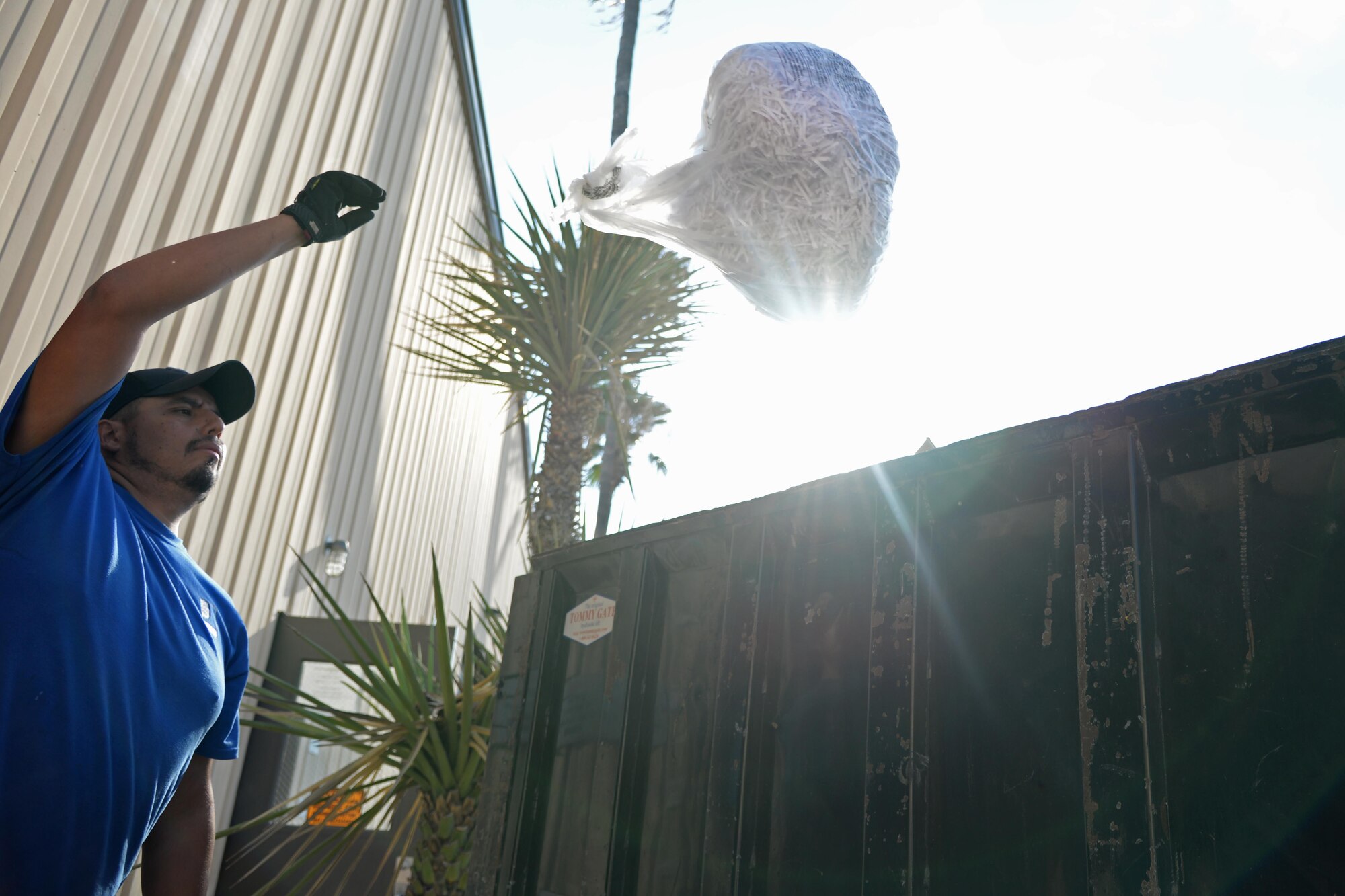 Roland Deleon, Laughlin Air Force Base, Texas recycler, tosses a bag of shredded paper into a flatbed at the aircraft engine workshop here. Last year, Laughlin saved more than 1,600 trees from being cut down by recycling used cardboard.