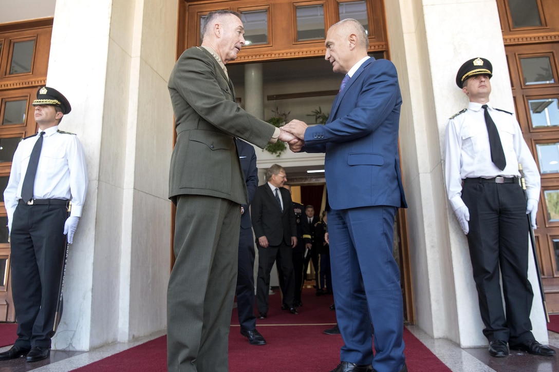 The chairman of the Joint Chiefs of Staff shanks hands with the Albanian president.