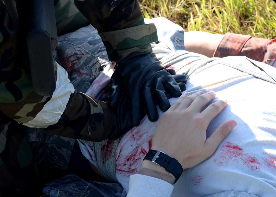Staff Sgt. Garriel Viera, 51st Security Forces defender, left, applies pressure to an abdominal wound of Airman 1st Class Steven May, 51st Medical Group medical technician, during a mass casualty scenario of exercise Beverly Herd 17-3 at Osan Air Base, Republic of Korea September 18, 2017. The scenario was designed to examine medical personnel’s and first responders’ ability to apply self-aid and buddy care on-scene and treat a number of casualties in an emergency. (U.S. Air Force photo by Tech Sgt. Ashley Tyler/Released)