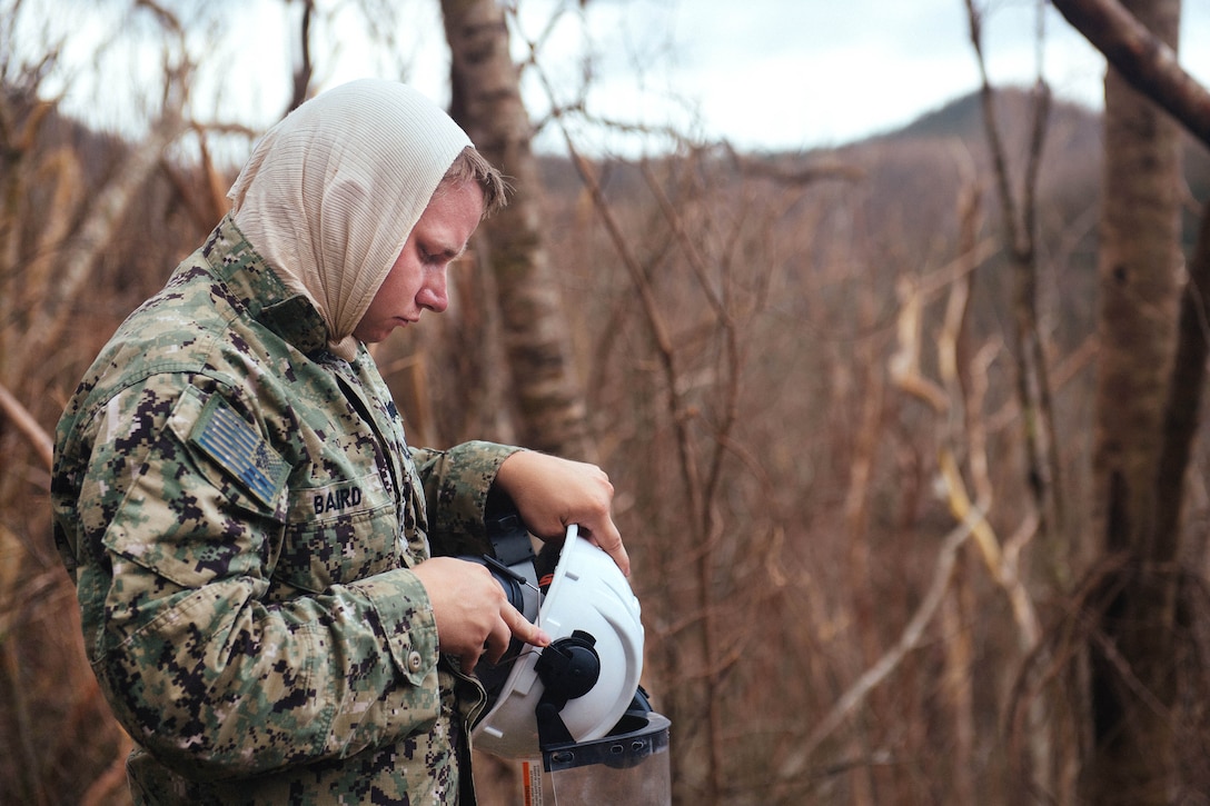 A sailor dons his personal protective equipment during before participating in road clearing operations.