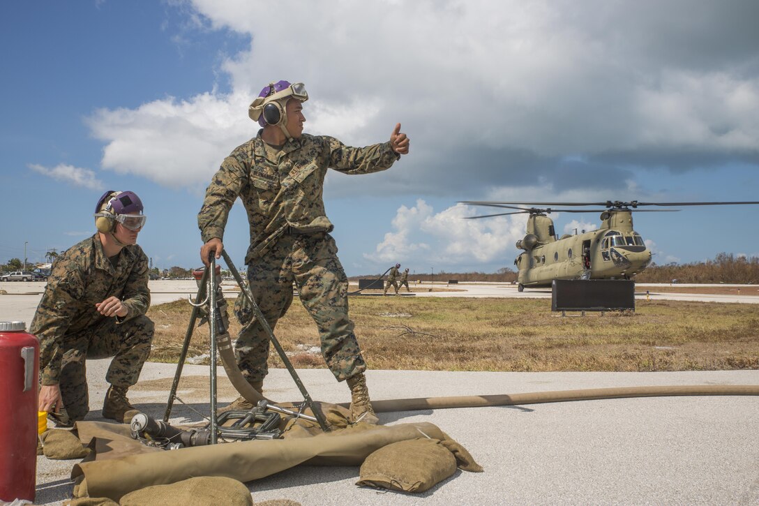 Lance Cpl. Sergio Hernandez, a bulk fuel specialist with Marine Wing Support Squadron 473, 4th Marine Aircraft Wing, Marine Forces Reserve, receives a signal from the crewmaster of the aircraft U.S. Army CH-47 Chinook, from Bravo Company, 1st Battalion, 111th Aviation Regiment to approach and begin refueling at the Florida Keys Marathon International Airport, in Marathon, Fla. Sept. 14, 2017.