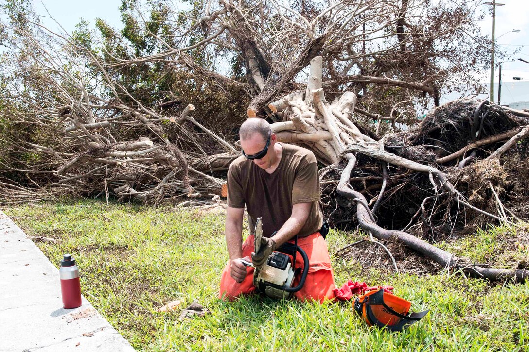 Petty Officer 2nd Class Ryan Budreau prepares to use a chain saw to help remove fallen trees felled by Hurricane Irma.