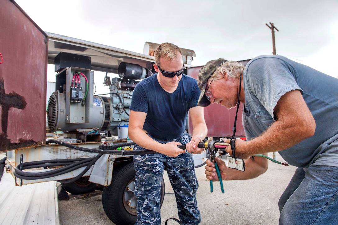 Navy Lt. j.g. Aaron Hampton, left, and Pat Segert, a civilian engineering contractor, work to restore power to a generator.