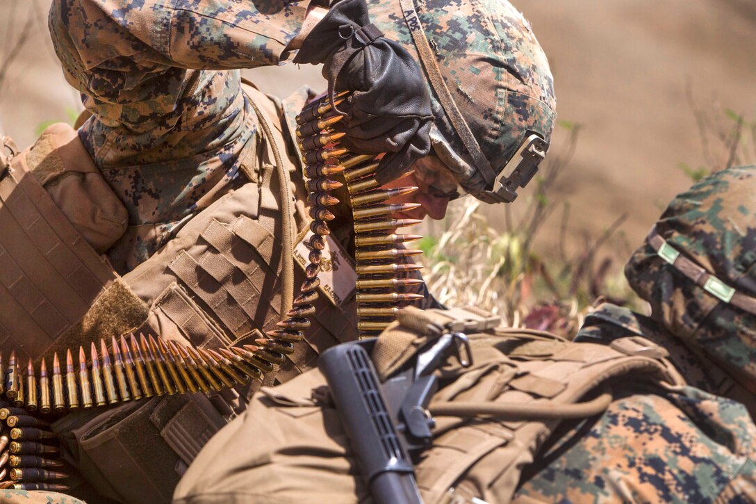 A Marine helps load a belt of 7.62 mm bullets for a M240B machine gun during an advanced infantry course.
