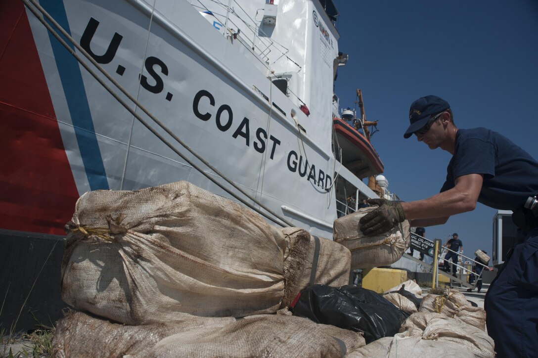 A Coast Guard Cutter Diligence crewmember stacks bales of cocaine in front of the Diligence in St. Petersburg, Florida, Sept. 17, 2017.