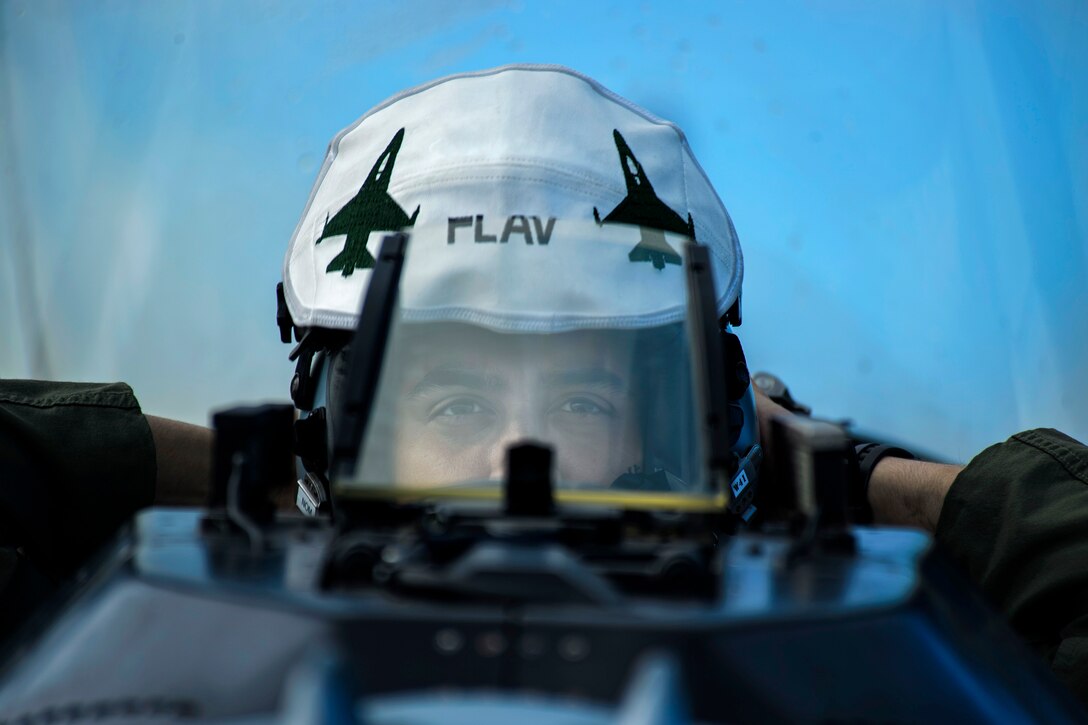 An Air Force dons his flight helmet before taxiing his F-16 Fighting Falcon aircraft.