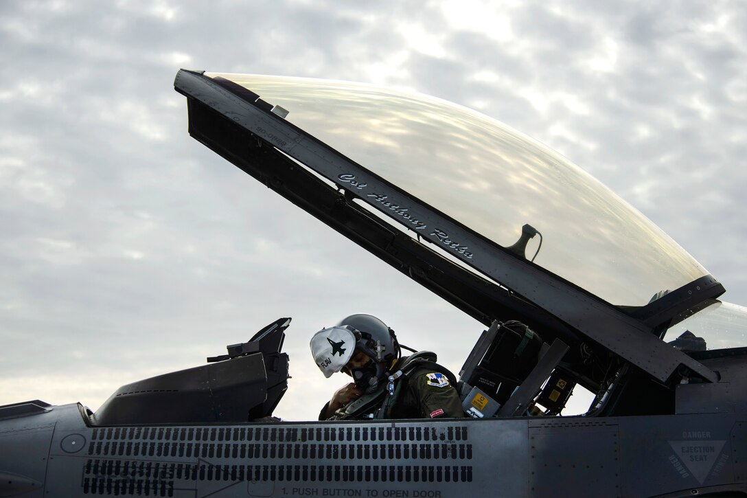 An Air Force pilot conducts pre-flight checks inside the cockpit of his F-16 Fighting Falcon aircraft.