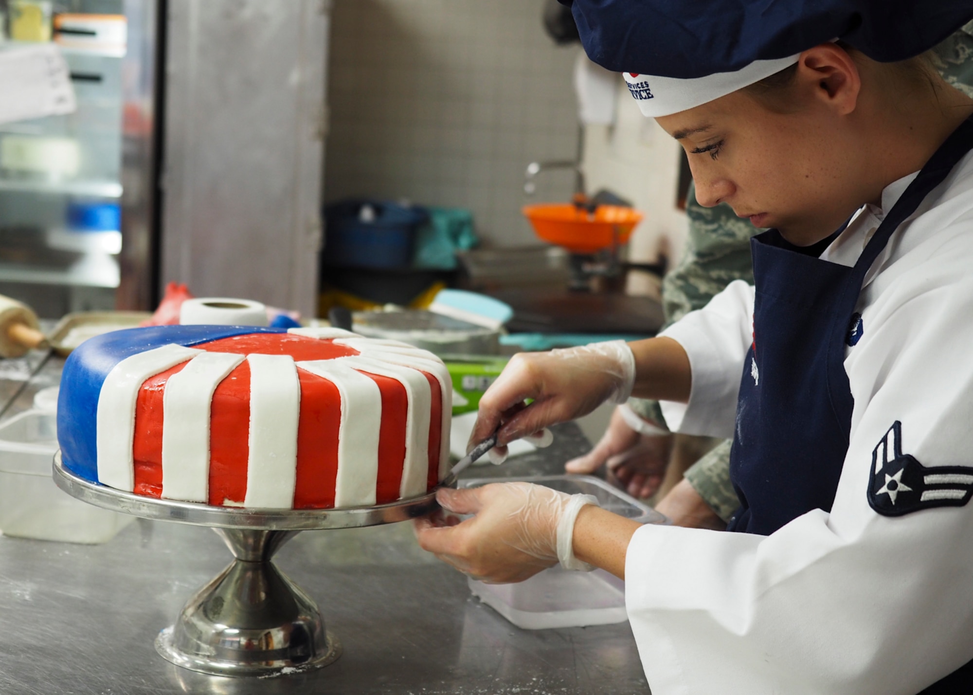 Airman 1st Class Kendall McGovern, 99th Force Support Squadron chef, prepares a layer of fondant on the Air Force's 70th anniversary celebration cake at Nellis Air Force Base, Nevada, September 17, 2017. McGovern spent more than two hours creating fondant stars and stripes to place around the multiple layers of cake. (U.S. Air Force photo by Master Sgt. Heidi West/Released)