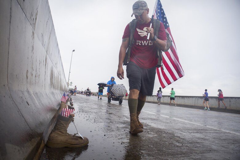 A run participate looks at a boot during the Fisher House Hero and Remembrance Run, Walk or Roll 8k on Ford Island aboard Joint Base Pearl Harbor-Hickam, Sept. 9, 2017. The road was adorned with over 7,500 military boots decorated with American flags, name tags with a photo of the service member, and information on the combat tour they were serving or where they were stationed. The free event was open to the public and military to honor those we have lost in the service since Sept. 11, 2001. (U.S. Marine Corps photo by Sgt. Zachary Orr)