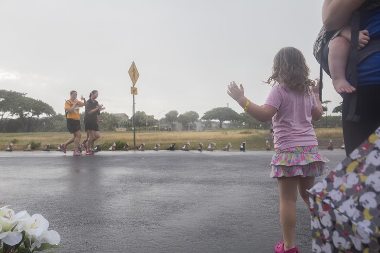A family stands on the side of the road to cheer on the run participants during the Fisher House Hero and Remembrance Run, Walk or Roll 8k on Ford Island aboard Joint Base Pearl Harbor-Hickam, Sept. 9, 2017. The road was adorned with over 7,500 military boots decorated with American flags, name tags with a photo of the service member, and information on the combat tour they were serving or where they were stationed. The free event was open to the public and military to honor those we have lost in the service since Sept. 11, 2001. (U.S. Marine Corps photo by Sgt. Zachary Orr)