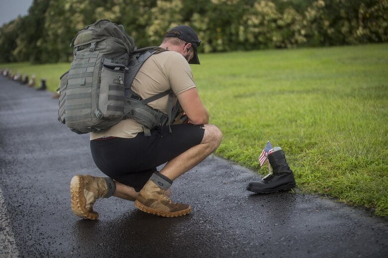A run participant kneels in front of a boot during the Fisher House Hero and Remembrance Run, Walk or Roll 8k on Ford Island, Joint Base Pearl Harbor-Hickam, Sept. 9, 2017. The road was adorned with over 7,500 military boots decorated with American flags, name tags with a photo of the Service member, and information on the combat tour they were serving or where they were stationed. The free event was open to the public and military to honor those we have lost in the Service since Sept. 11, 2001. (U.S. Marine Corps photo by Sgt. Zachary Orr)
