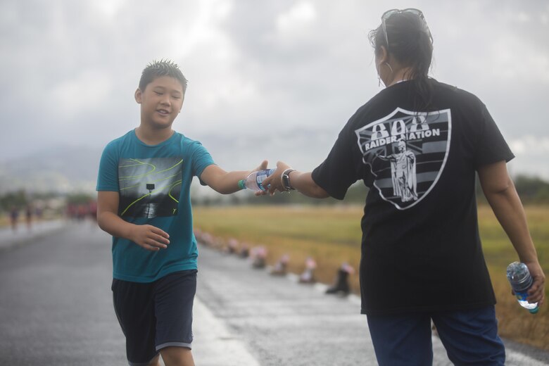 A run participant grabs a bottle of water during the Fisher House Hero and Remembrance Run, Walk or Roll 8k on Ford Island aboard Joint Base Pearl Harbor-Hickam, Sept. 9, 2017. The road was adorned with over 7,500 military boots decorated with American flags, name tags with a photo of the service member, and information on the combat tour they were serving or where they were stationed. The free event was open to the public and military to honor those we have lost in the service since Sept. 11, 2001. (U.S. Marine Corps photo by Sgt. Zachary Orr)