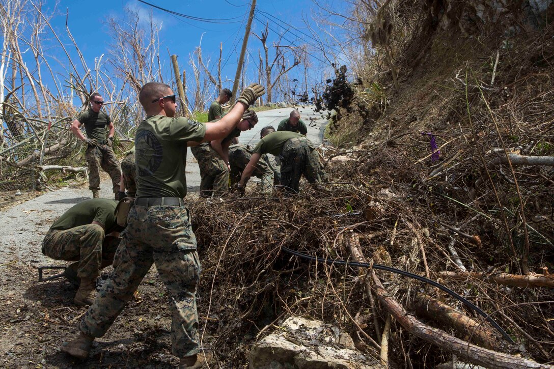 U.S. Marine Corps Pfc. Jameson E. Kovacs, a mortarman with Battalion Landing Team 2nd Battalion, 6th Marine Regiment, 26th Marine Expeditionary Unit (MEU), throws debris away from a roadway to allow vehicles to navigate safely in a community affected by Hurricane Irma in St. John, U.S. Virgin Islands, Sept. 17, 2017. The 26th MEU is supporting authorities in the U.S. Virgin Islands with the combined goal of protecting the lives and safety of those in affected areas. (U.S. Marine Corps photo by Lance Cpl. Santino D. Martinez)