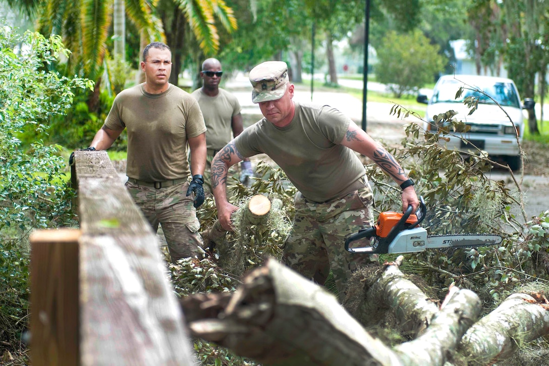 Soldiers clean up tree branches in the wake of Hurricane Irma.