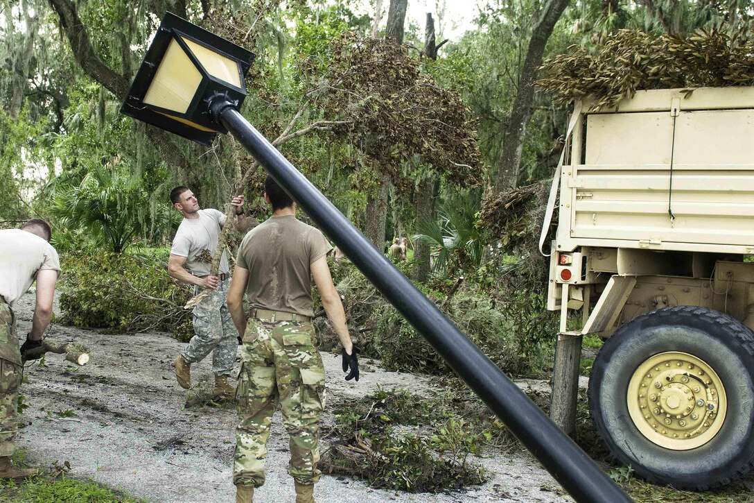 Soldiers clean up tree branches in the wake of Hurricane Irma.