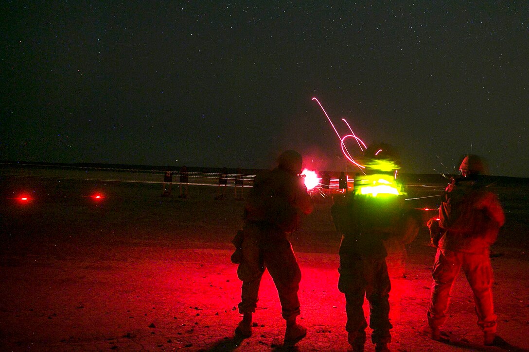 Marines fire weapons at night.