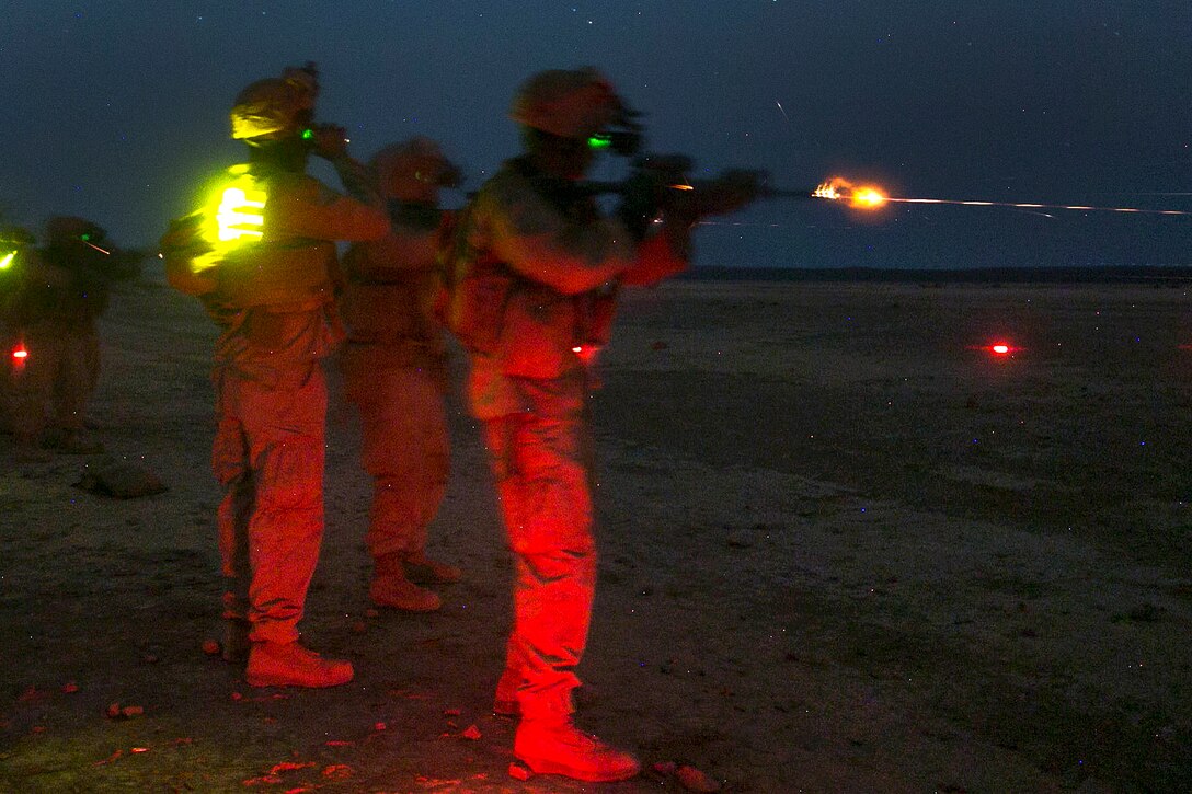 Marines fire weapons at night.