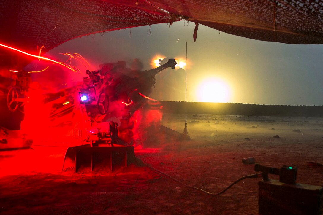 Marines participate fire a howitzer at night.
