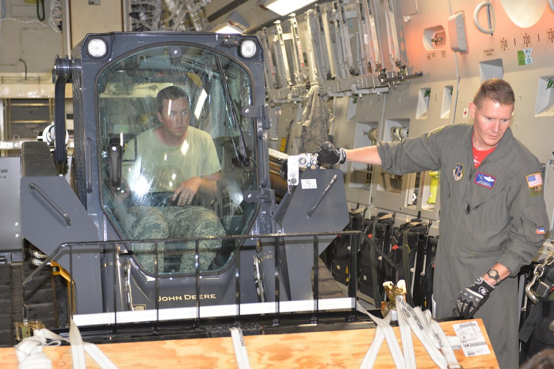 U.S.  Air Force Staff Sgt. Travis Albee, Air Transportation Craftsman, 157th Logistics Readiness Squadron, New Hampshire Air National Guard, operates a skid steer as Master Sgt. Brian Hamilton, Loadmaster, 183rd Airlift Wing, Mississippi Air National Guard, guides him onto a C-17A Globemaster. The skid steer is part of the Disaster Relief Bed Down Kit (DRBS) deploying from Pease ANGB. to the Virgin Islands in support of the Irma relief effort.  The DRBS kit is one of two kits stored here at Pease Air National Guard Base.  (N.H. Air National Guard Photo by Master Sgt. Thomas Johnson)