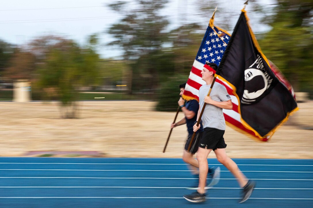 Airmen carry flags during the POW/MIA Recognition Day ceremony run.