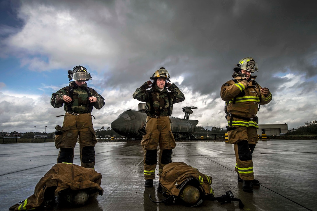 Three firefighters put protective gear on.