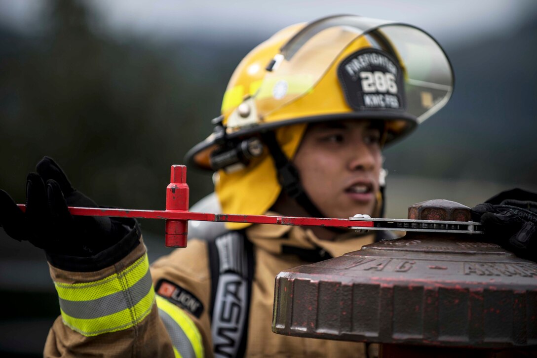 A fireman uses a wrench to turn a bolt.