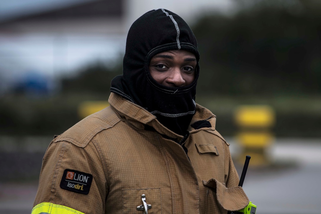 A firefighter wearing protective gear looks at the camera.