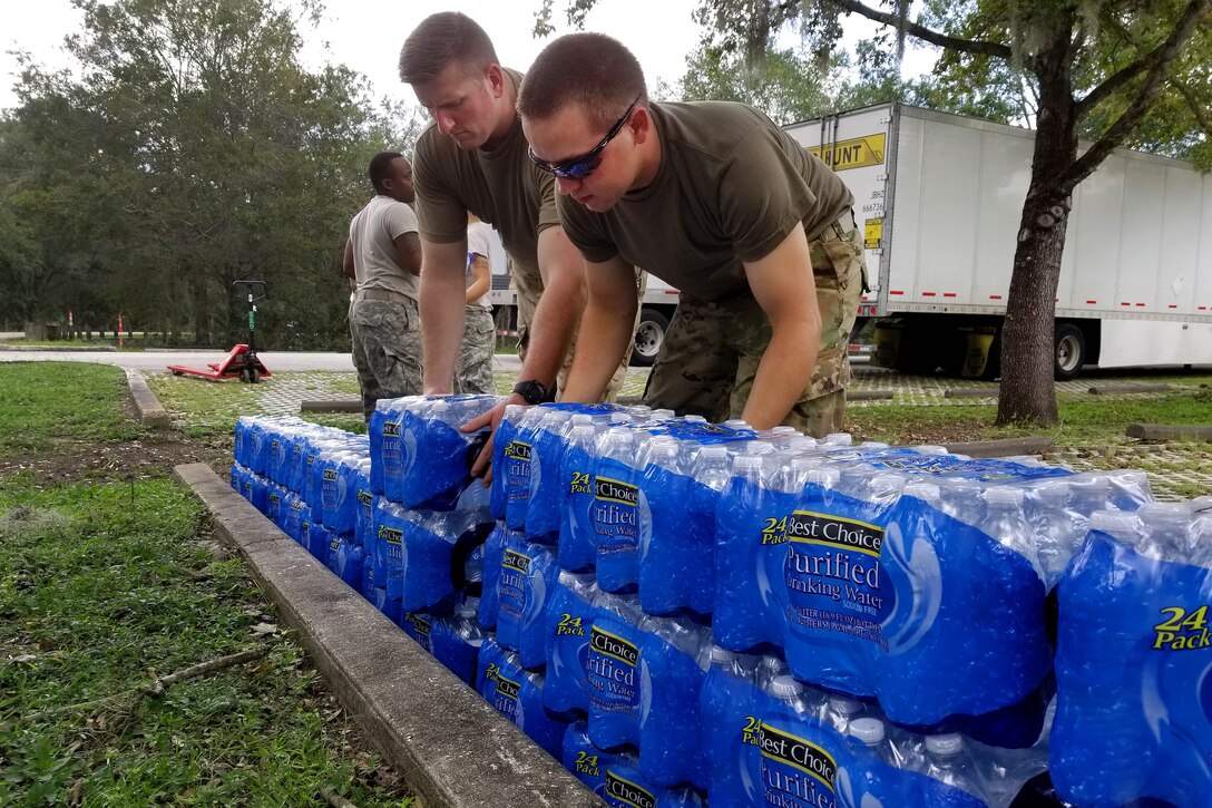 Guardsmen stack cases of water to be distributed to residents.