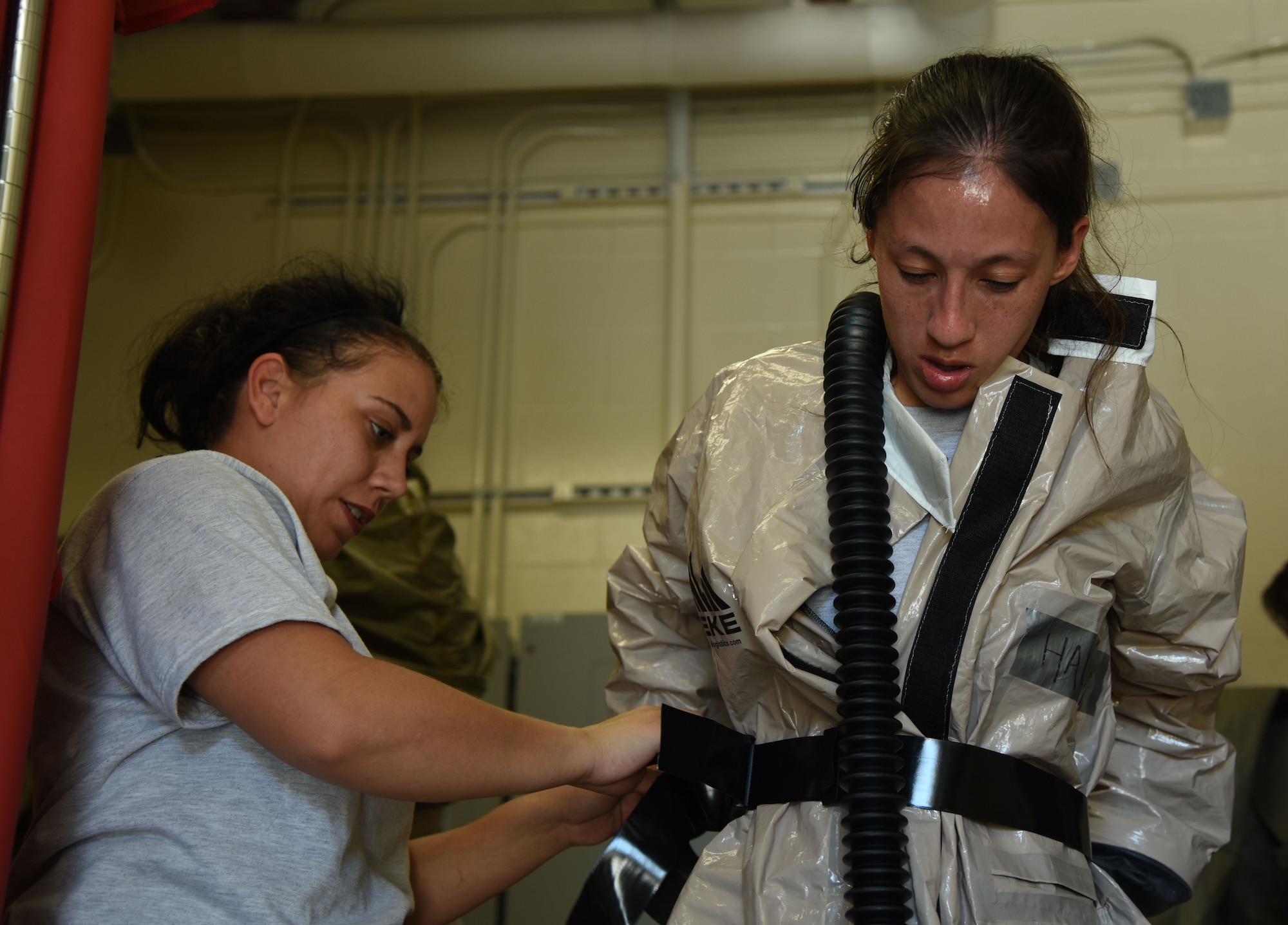 Senior Airman Jessica Knott, 81st Dental Squadron dental lab technician, assists  Senior Airman Anna Halcin, 81st Surgical Operations Squadron medical technician, dress in decontamination gear during the 81st Medical Group integrated in-place patient decontamination training course behind the Keesler Medical Center Sept. 14, 2017, on Keesler Air Force Base, Mississippi. The two-day course trained 21 personnel, which came from four different disaster medical teams: IPPD, triage, manpower and security. Throughout the training, they learned to utilize Keesler’s fixed decontamination facility and how to set up and tear down the decontamination tent. (U.S. Air Force photo by Kemberly Groue)