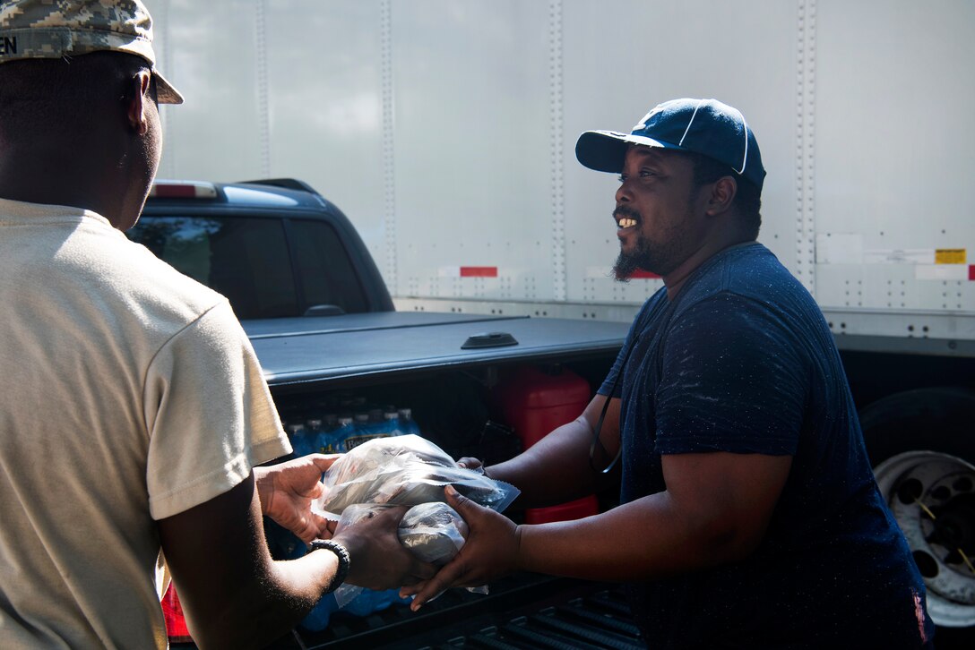 Guardsman distributes food and water to a resident.