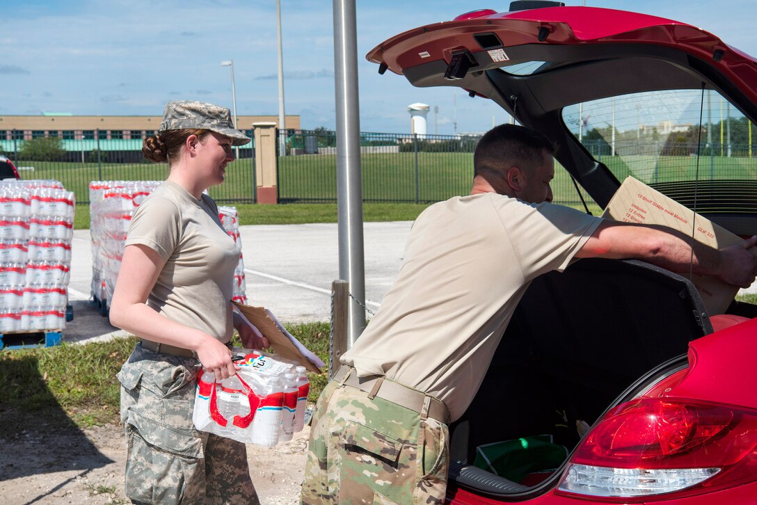 Guardsmen distribute food and water to residents.