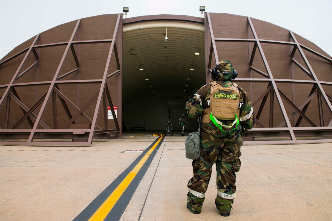 An airman stands outside of a building.